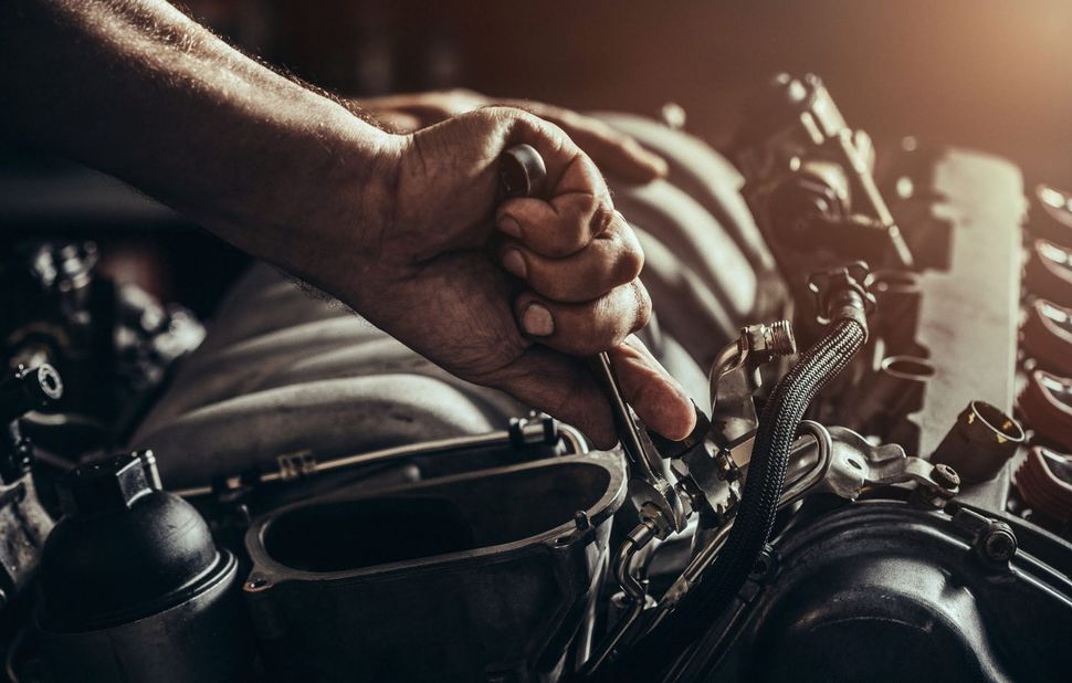 Primo piano di una mano che impugna il manubrio e l'acceleratore di una motocicletta, con parti del motore visibili.