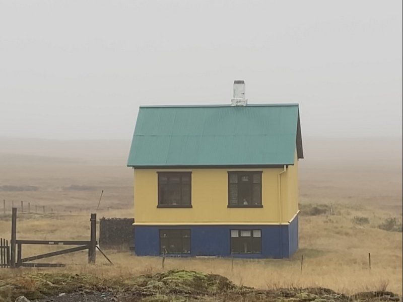 Ein gelbes und blaues Haus mit einem grünen Dach