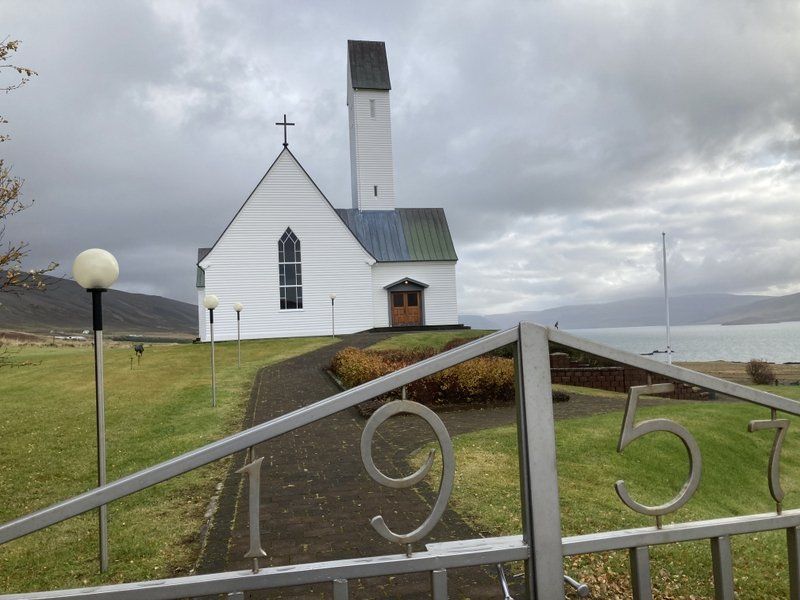 Hinter einem Zaun steht eine weiße Kirche mit der Nummer 195