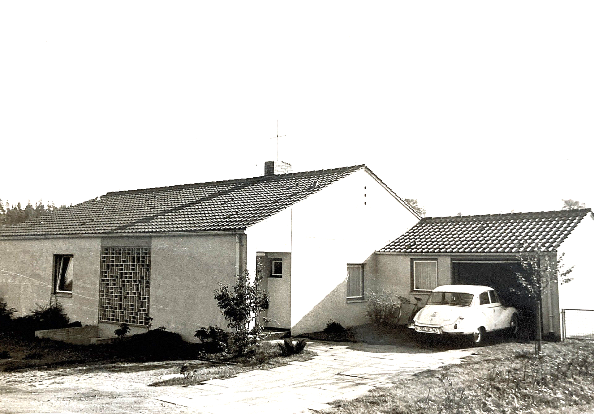 Ein Schwarzweißfoto eines Hauses mit einem davor geparkten Auto