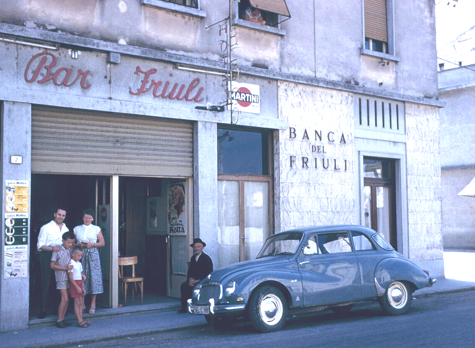 Ein blaues Auto steht vor einem Gebäude mit der Aufschrift „Bar Friuli“