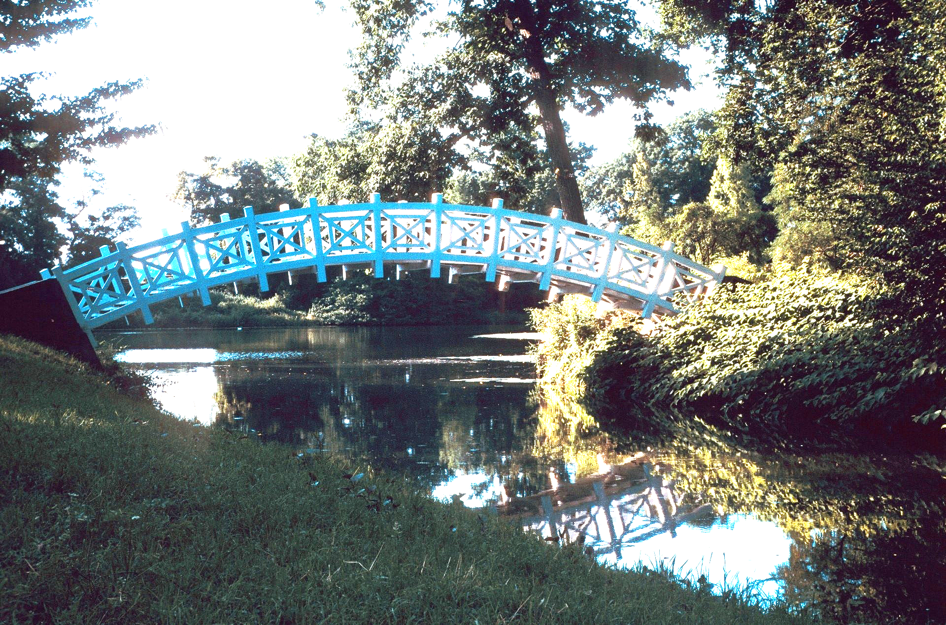 Eine blaue Brücke über ein Gewässer mit Bäumen im Hintergrund
