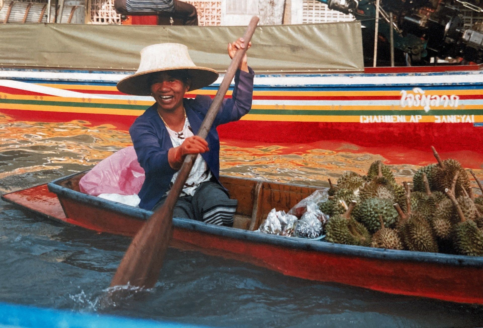 Ein Mann mit Hut rudert ein Boot voller Durian