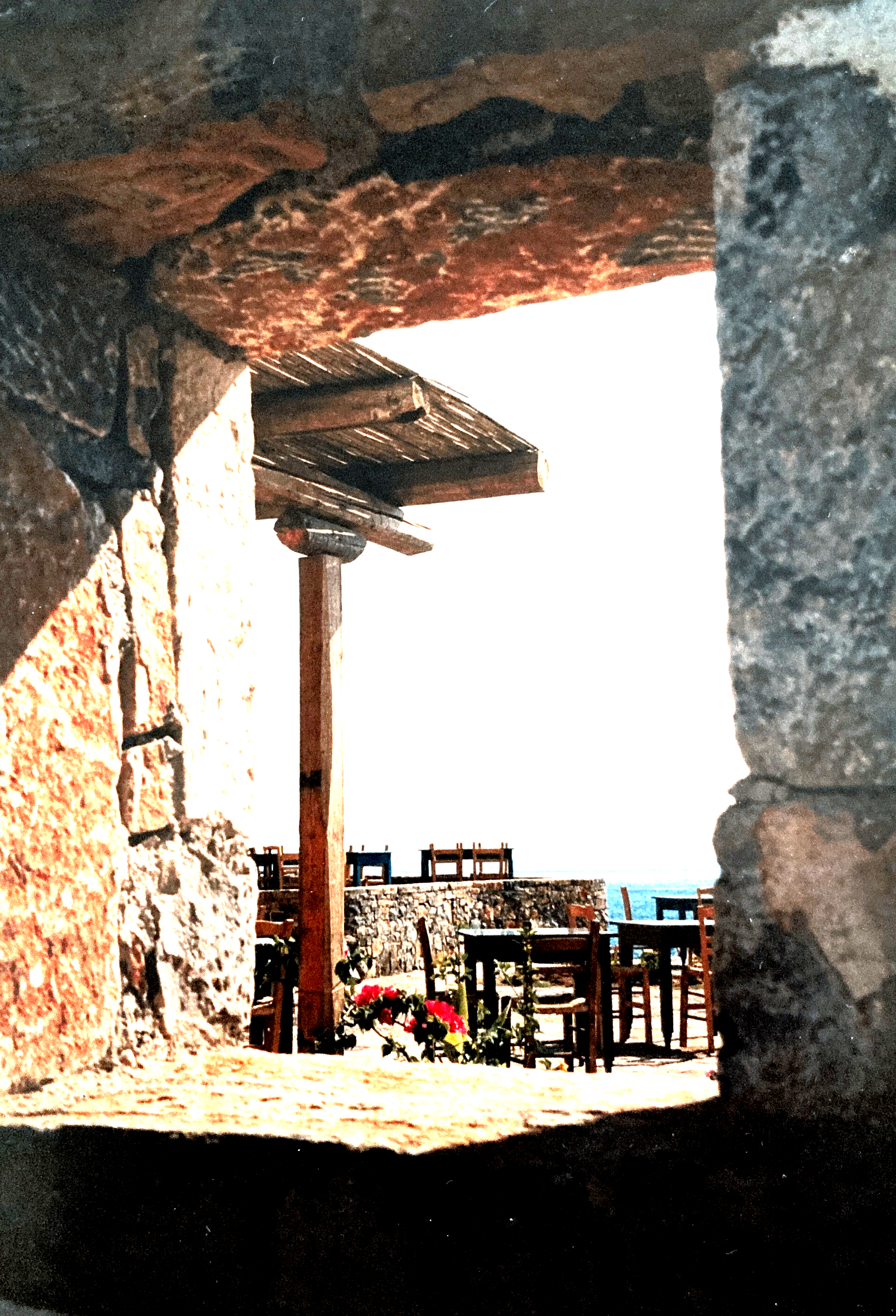 Blick durch eine Steinmauer auf einen Tisch und Stühle