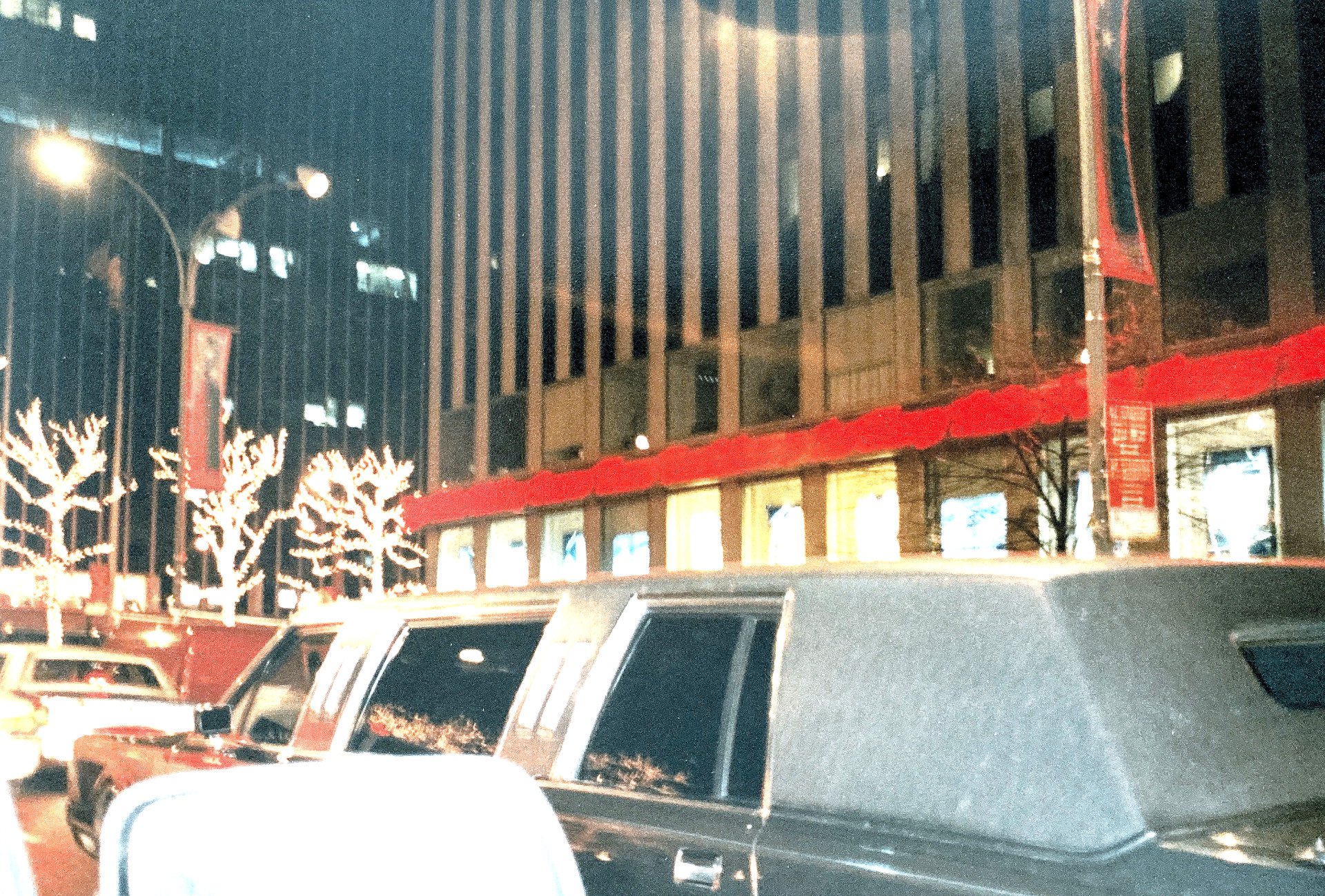 Eine Reihe von Autos parkt nachts vor einem Gebäude