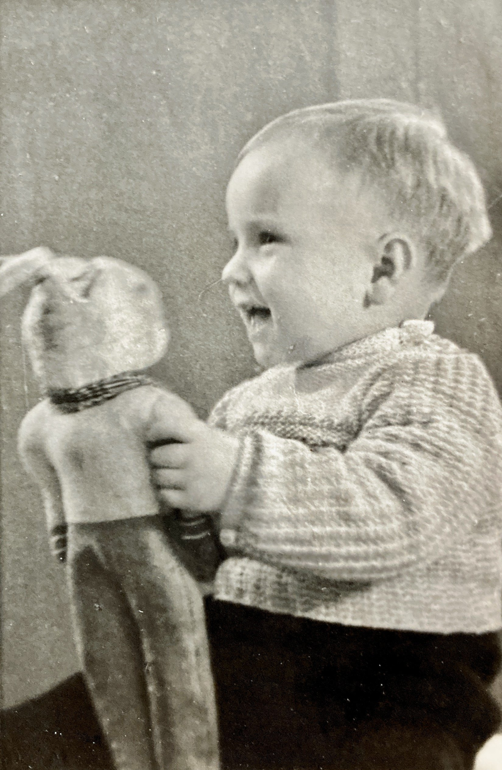 Ein Schwarzweißfoto eines Babys, das eine Puppe hält.