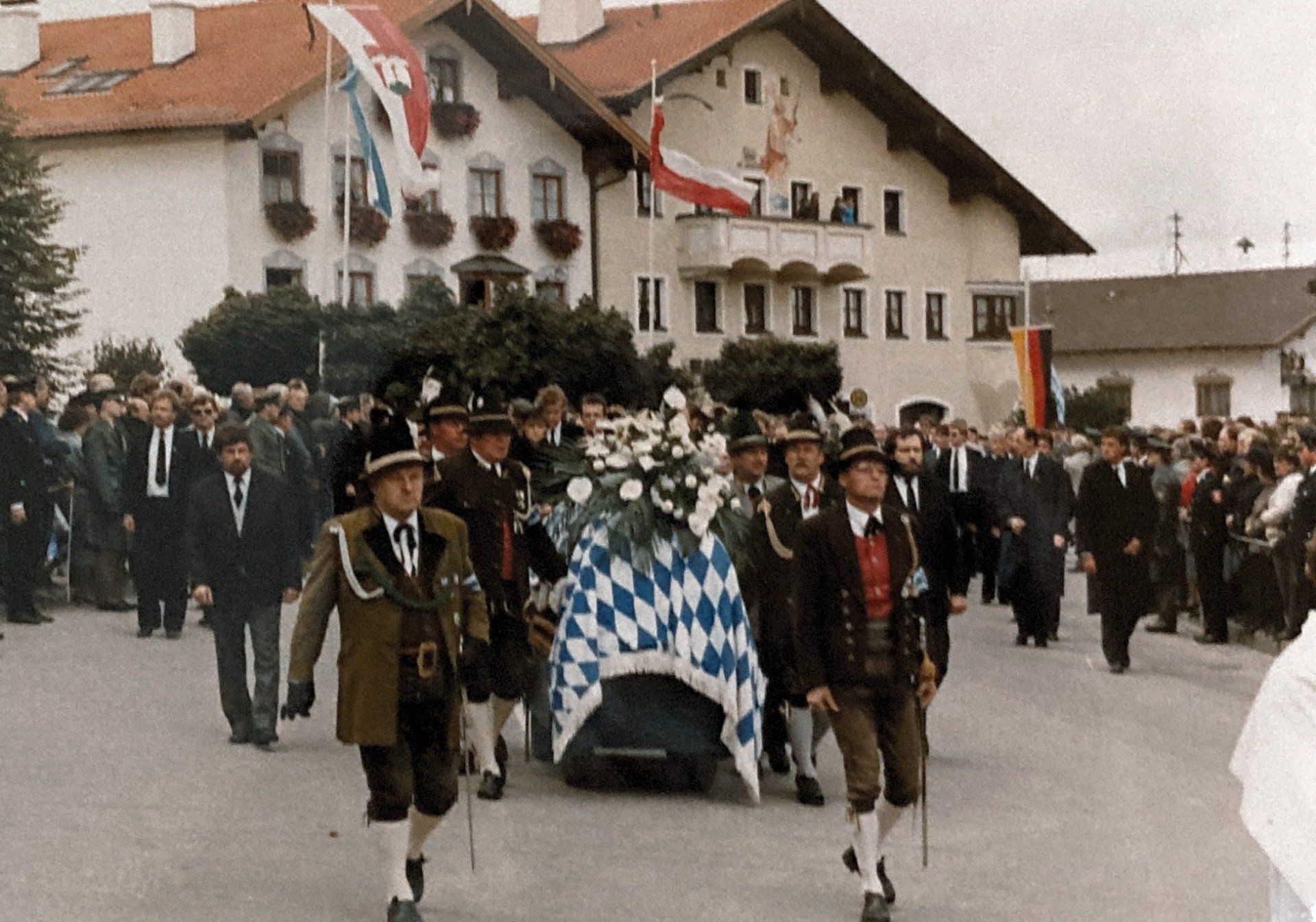 Eine Gruppe von Männern marschiert mit einem Sarg eine Straße entlang