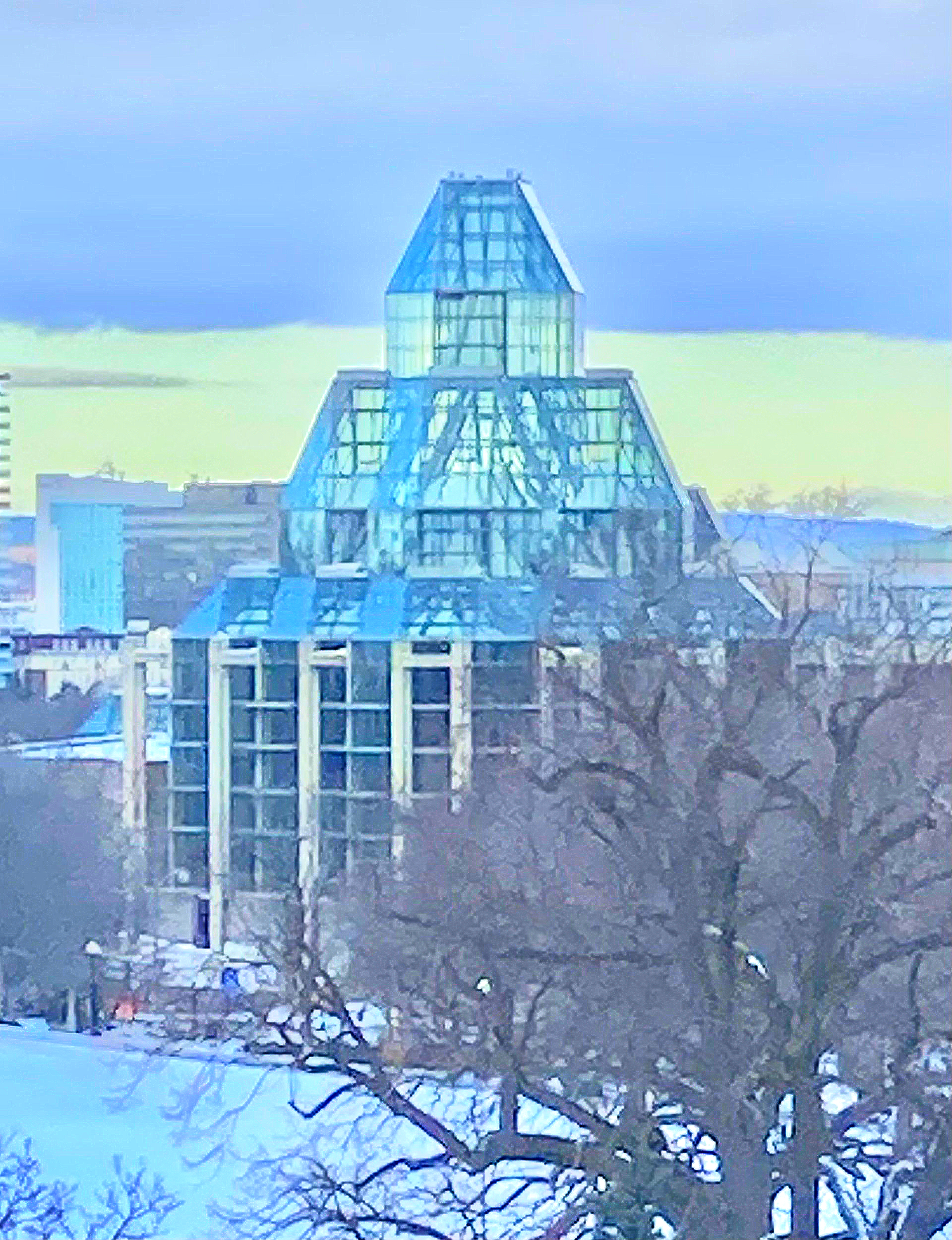 Ein großes Gebäude mit einer pyramidenförmigen Spitze ist von Schnee und Bäumen umgeben.