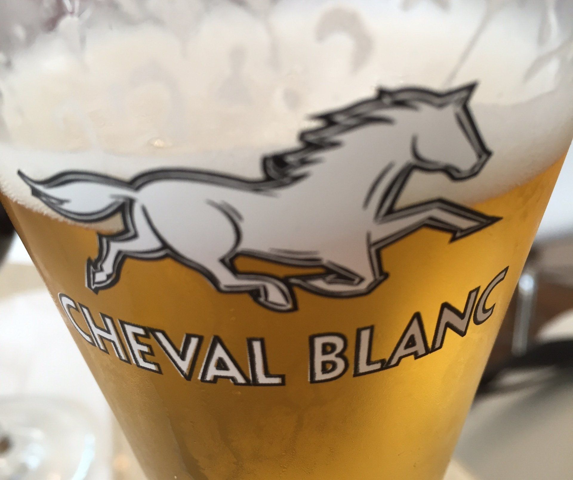 Ein Glas Cheval Blanc Bier mit einem Pferd darauf