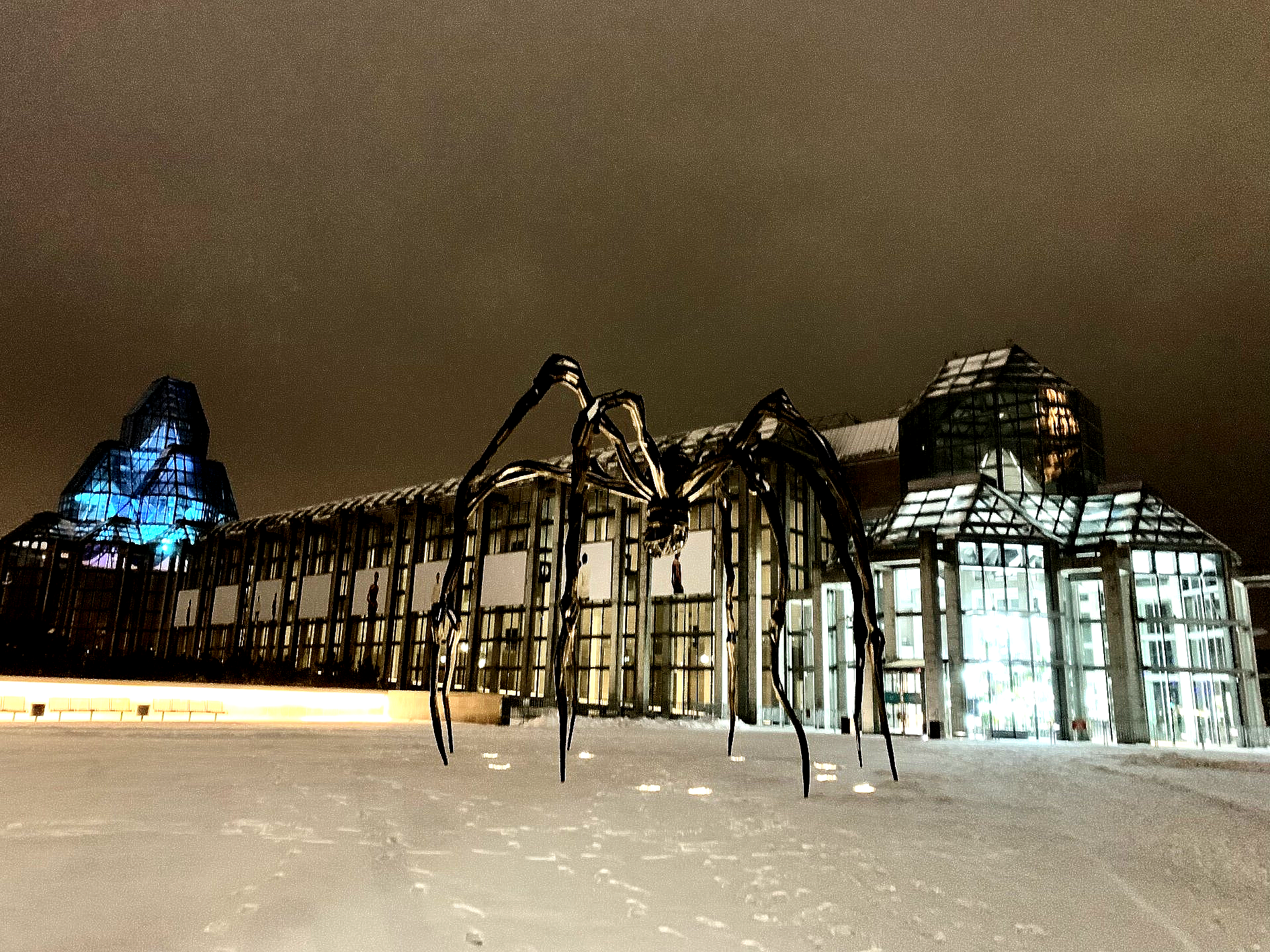 Eine riesige Spinnenstatue vor einem Gebäude in der Nacht