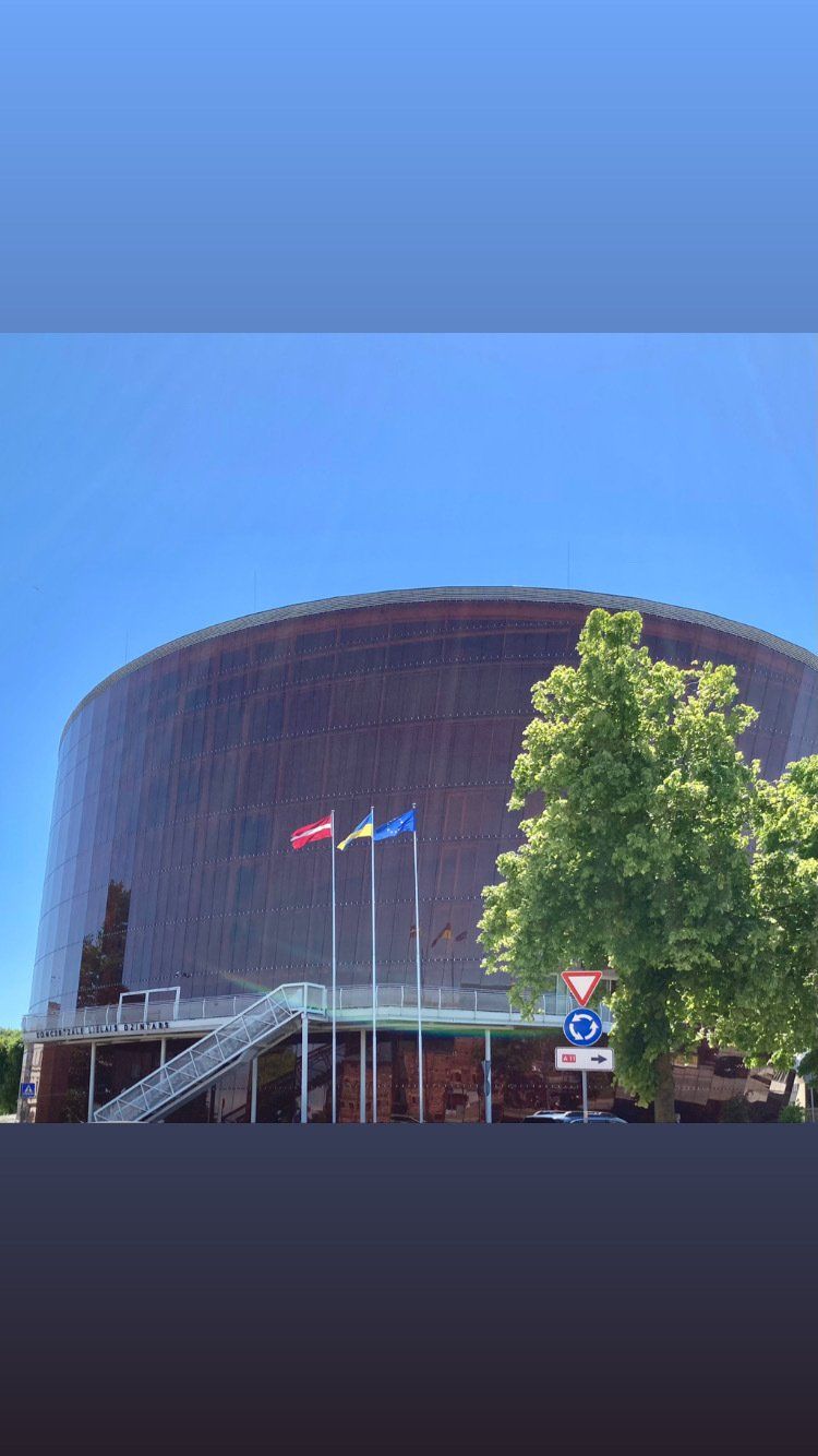 Ein großes Gebäude, vor dem drei Flaggen wehen.