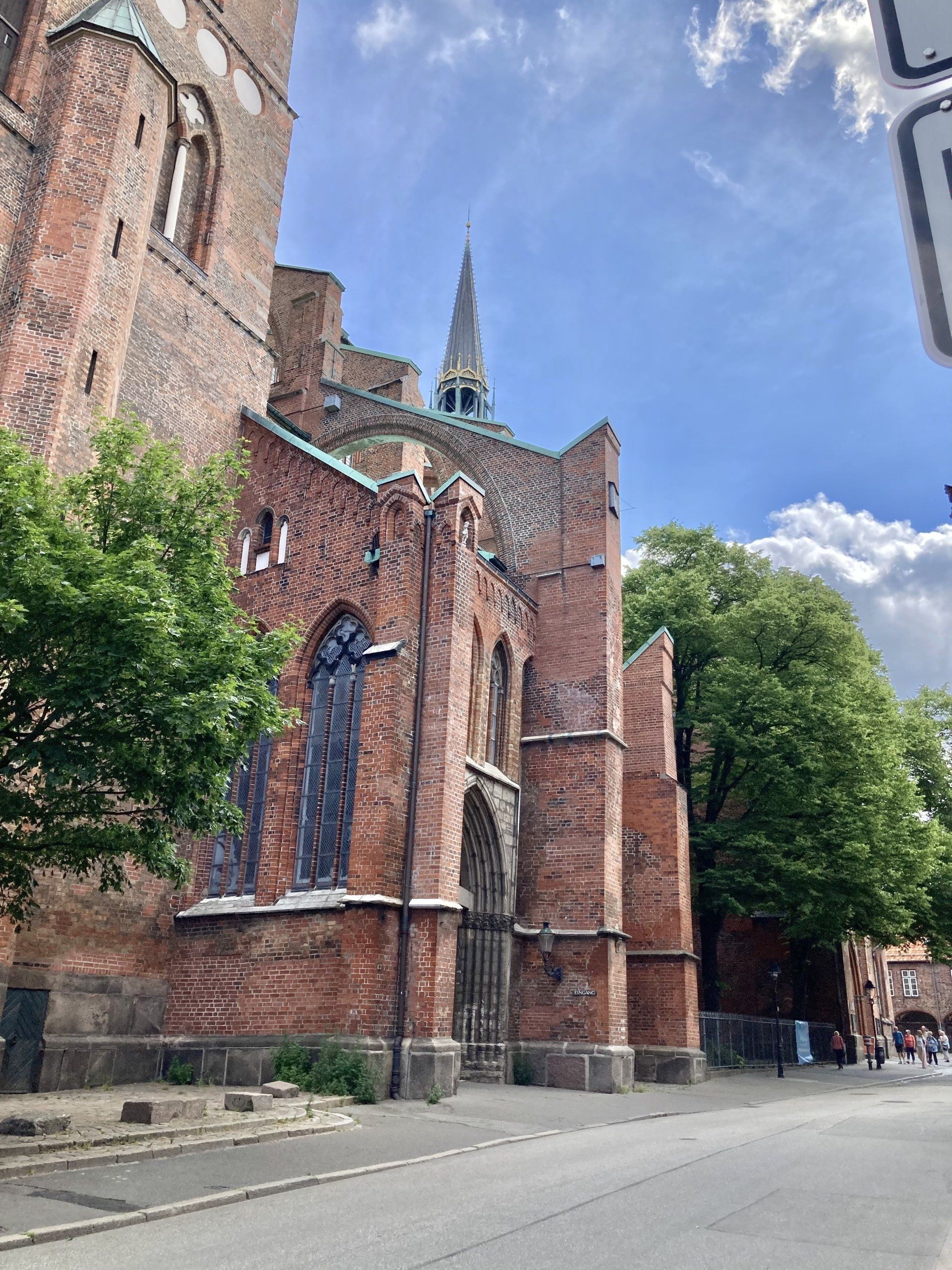 Am Straßenrand steht ein großes Backsteingebäude mit einem Kirchturm.