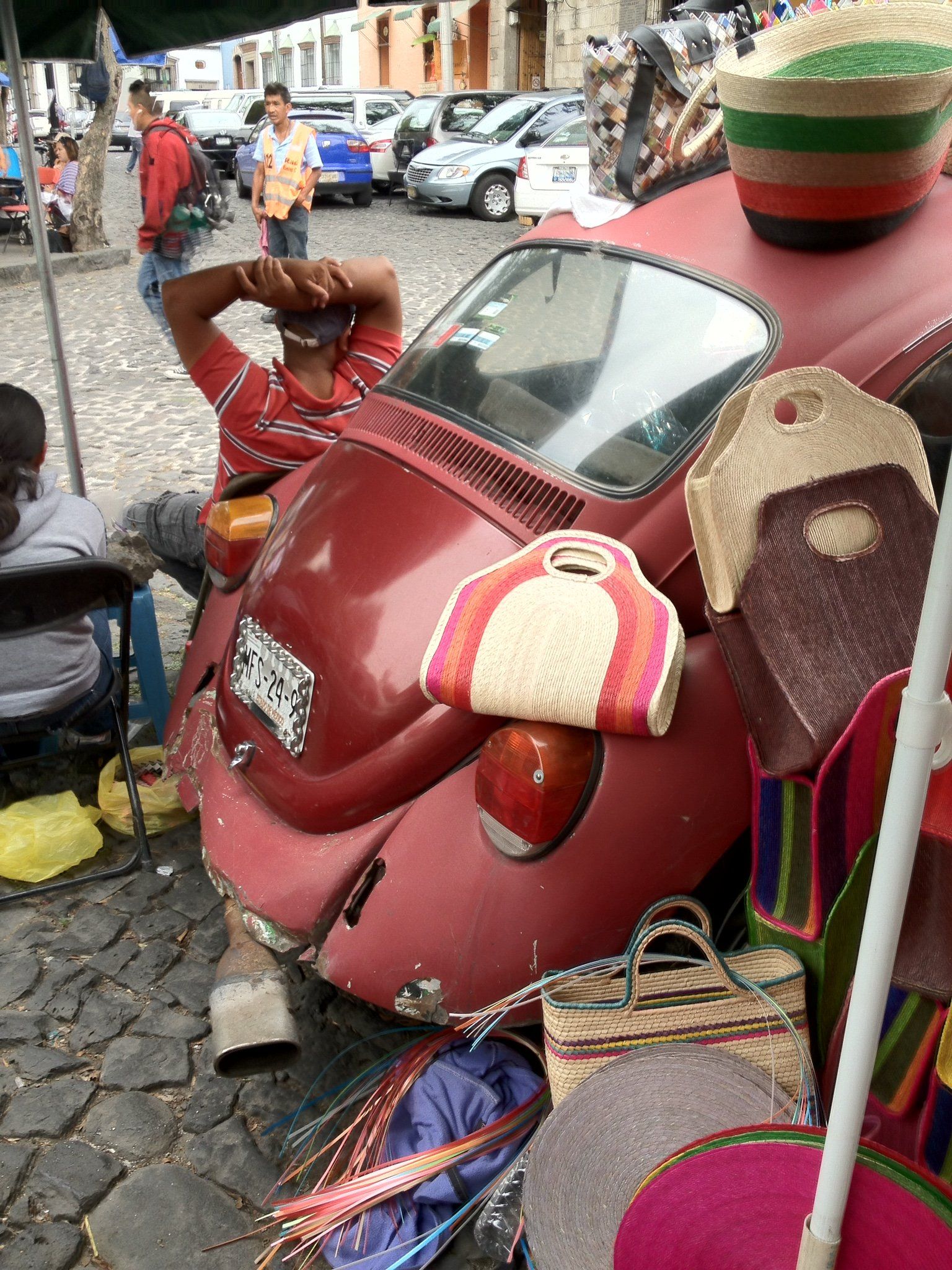 Ein Mann sitzt auf der Motorhaube eines roten Autos