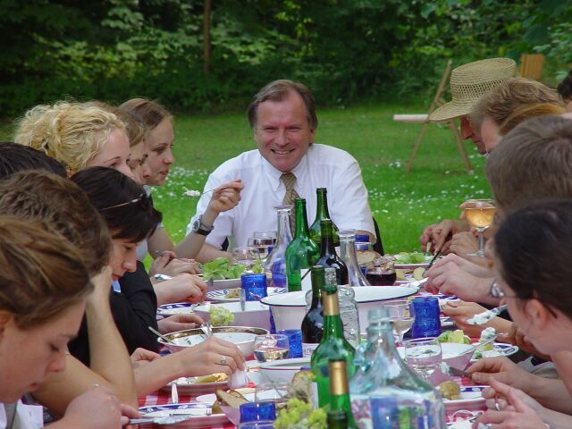 Eine Gruppe von Menschen sitzt mit Weinflaschen um einen Tisch herum