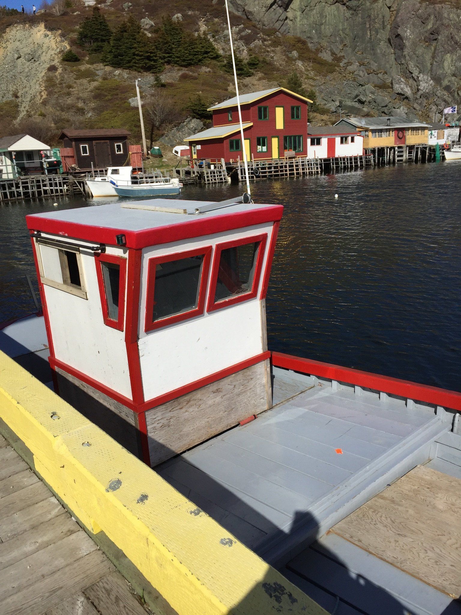 Ein kleines rot-weißes Boot liegt an einem Dock