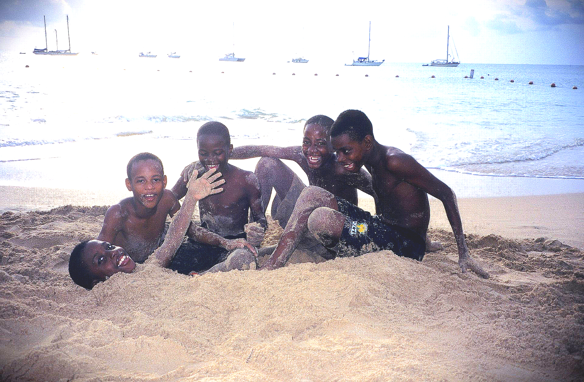 Eine Gruppe junger Jungen liegt im Sand an einem Strand.