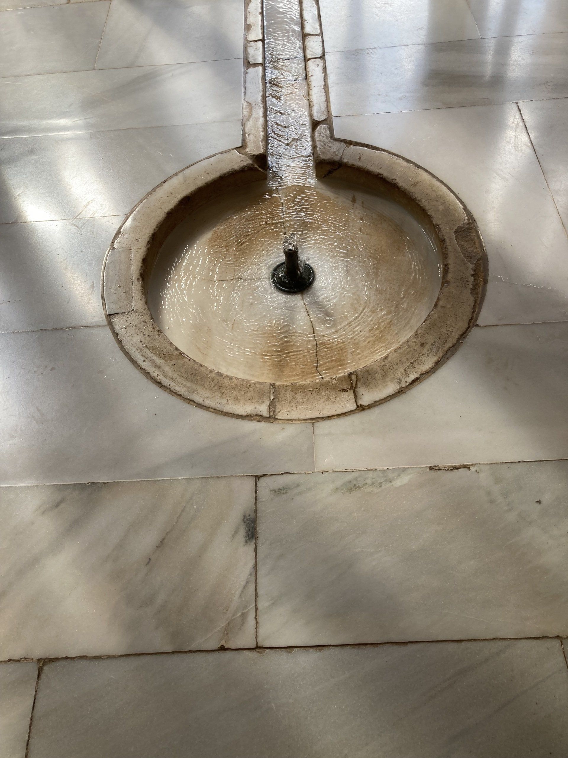 Ein Brunnen auf einem gefliesten Boden, aus dem Wasser kommt