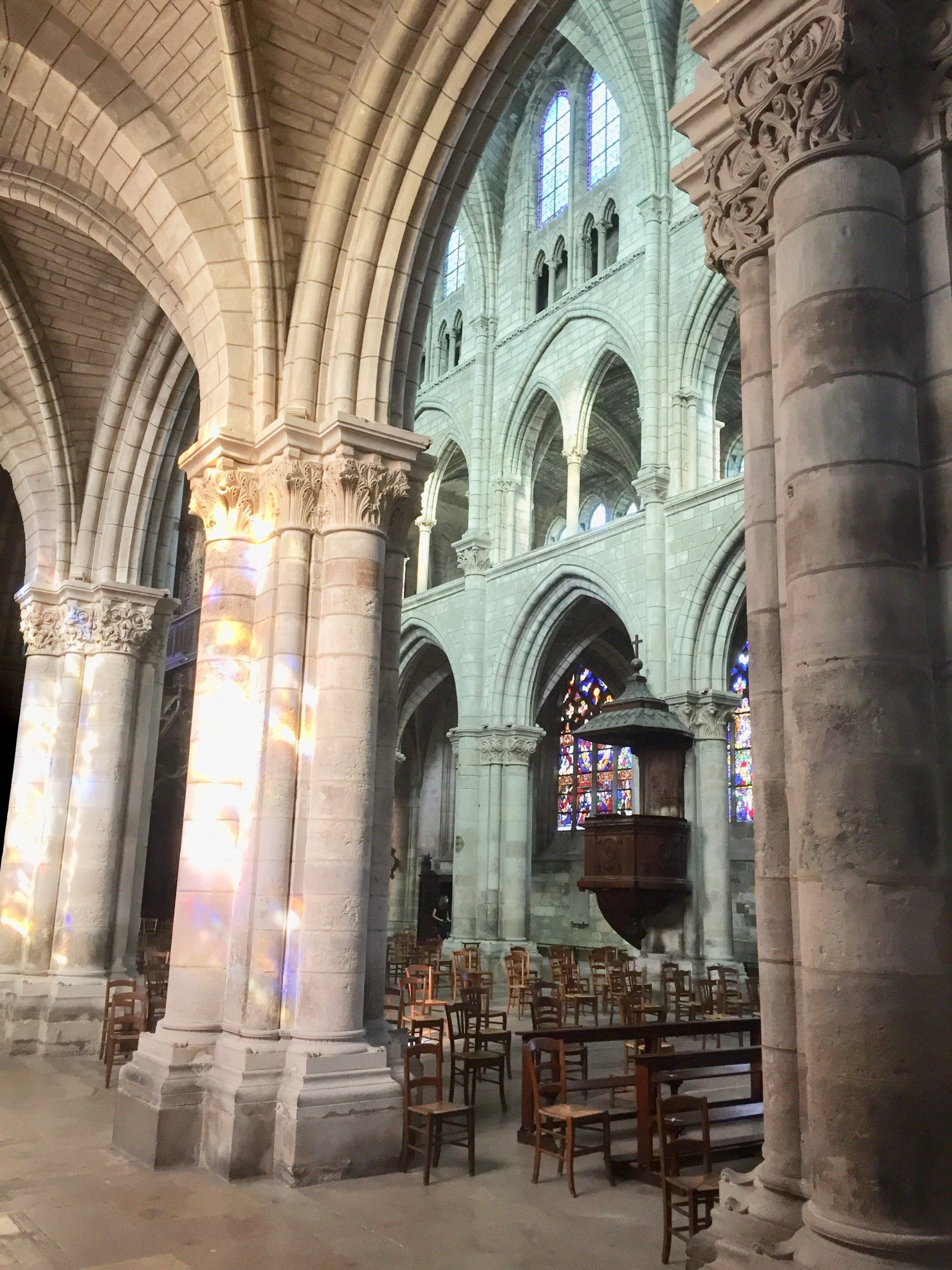 Das Innere einer Kirche mit Säulen und Buntglasfenstern.