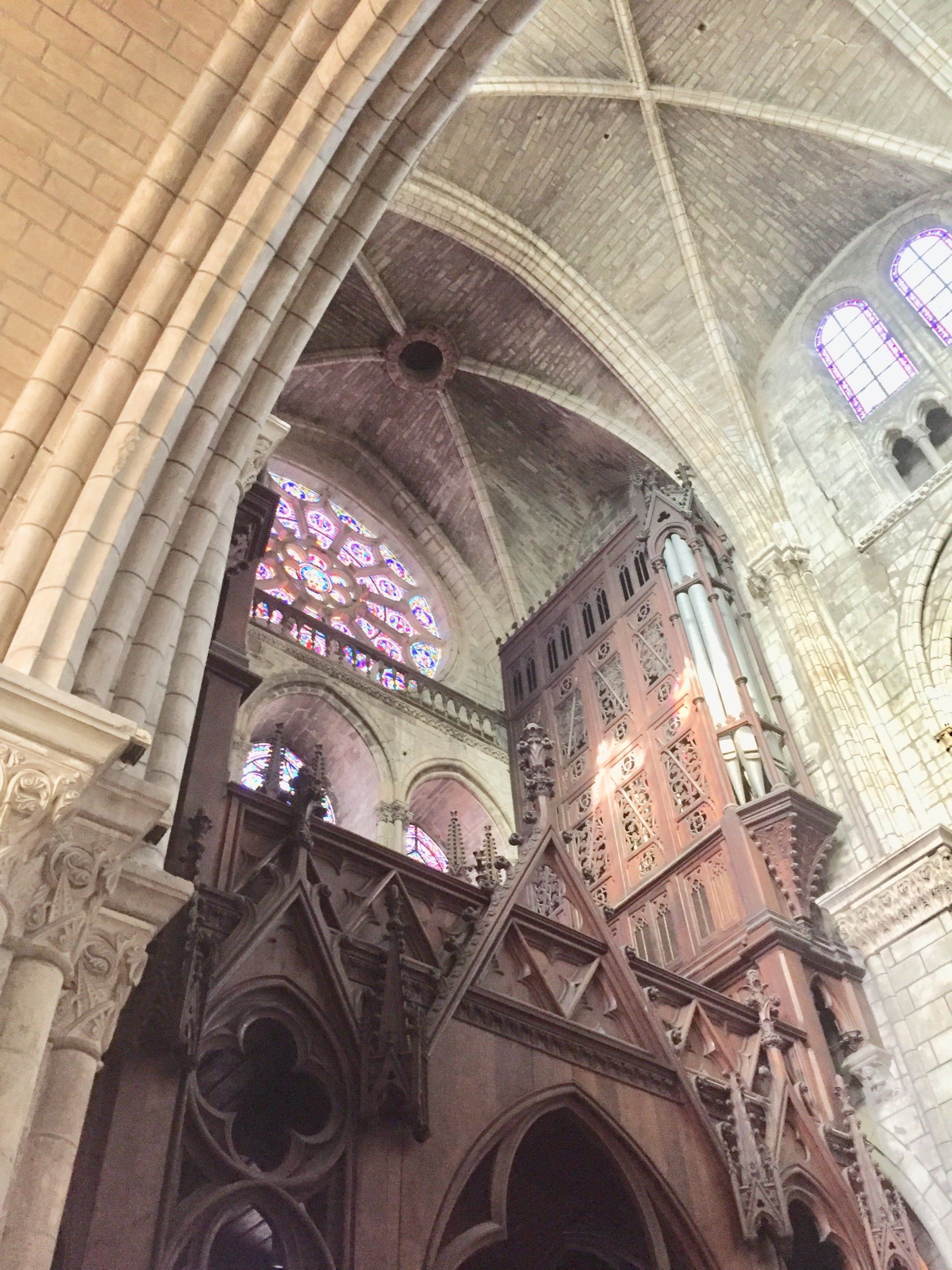 Blick nach oben zur Decke einer Kirche mit Buntglasfenstern.