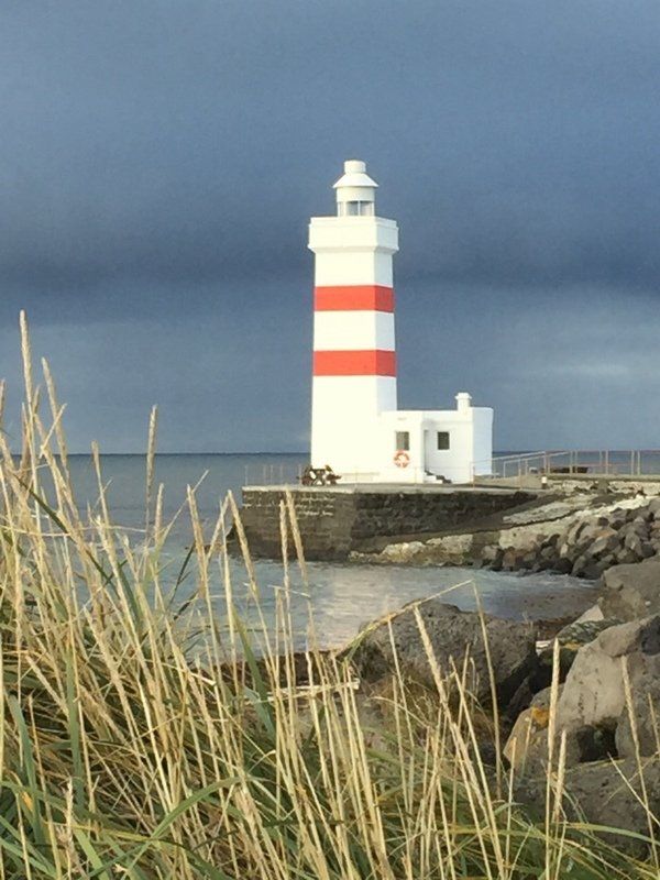 Ein rot-weißer Leuchtturm steht am Ufer eines Gewässers.