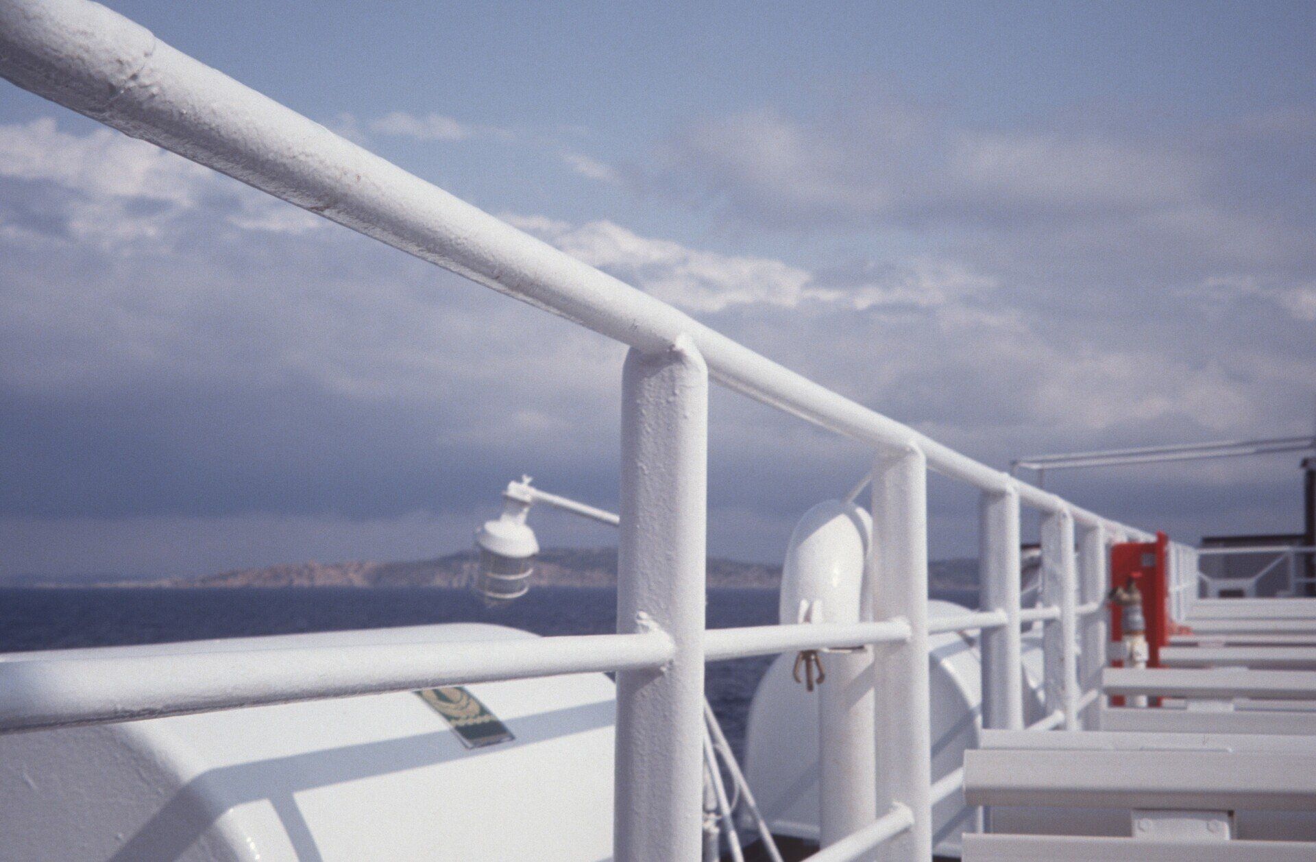 Ein weißes Geländer auf einem Boot mit Blick auf den Ozean