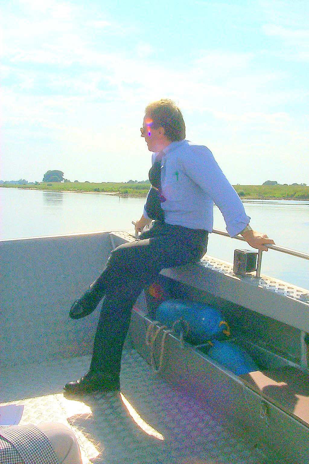 Ein Mann sitzt an der Seite eines Bootes und schaut aufs Wasser.