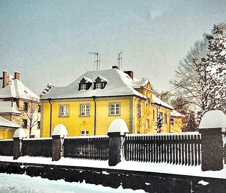 Eine verschneite Landschaft mit einem gelben Haus im Vordergrund