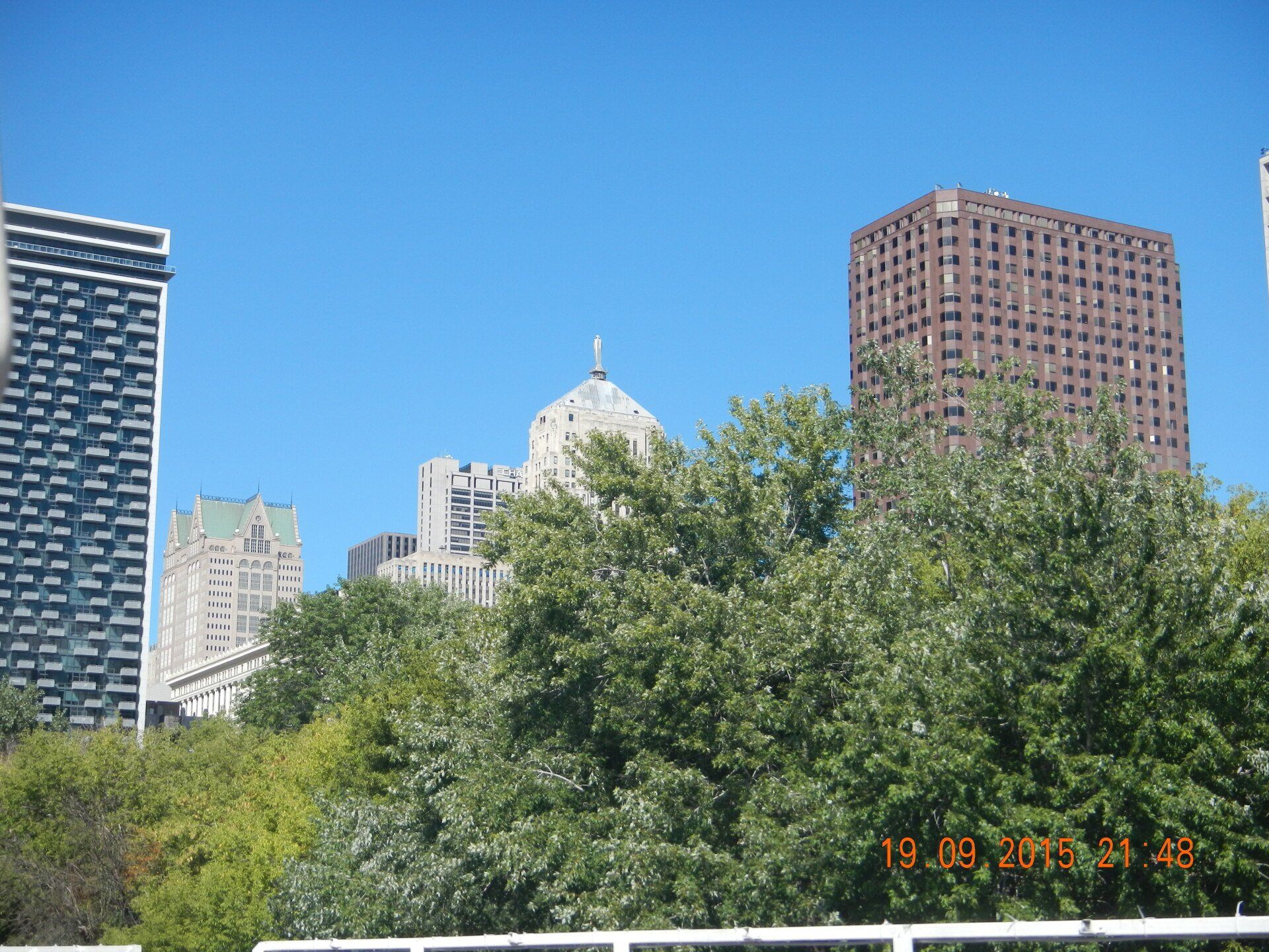 Eine Skyline der Stadt mit Bäumen im Vordergrund und einem blauen Himmel im Hintergrund