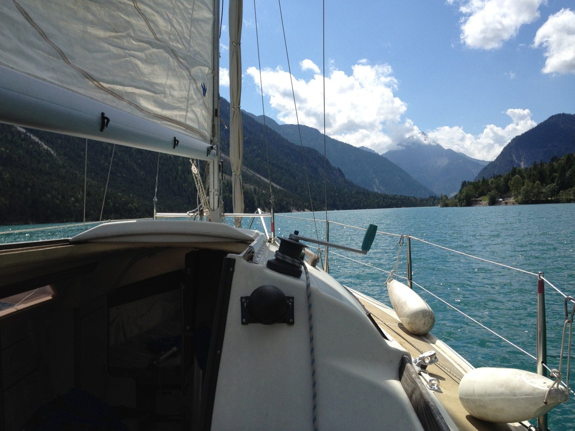 Ein Segelboot schwimmt auf einem See mit Bergen im Hintergrund