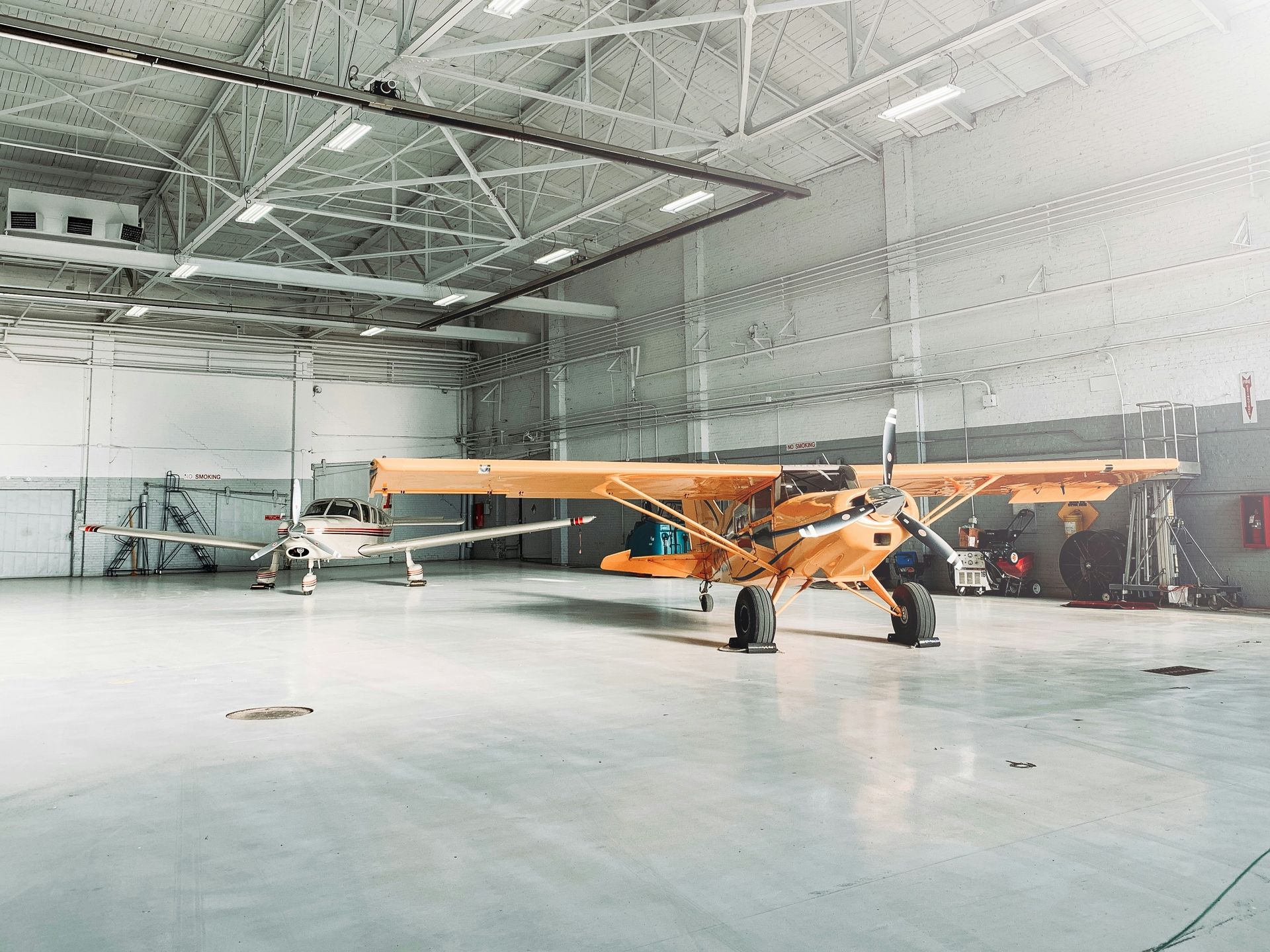 A small yellow airplane is parked in a hangar.