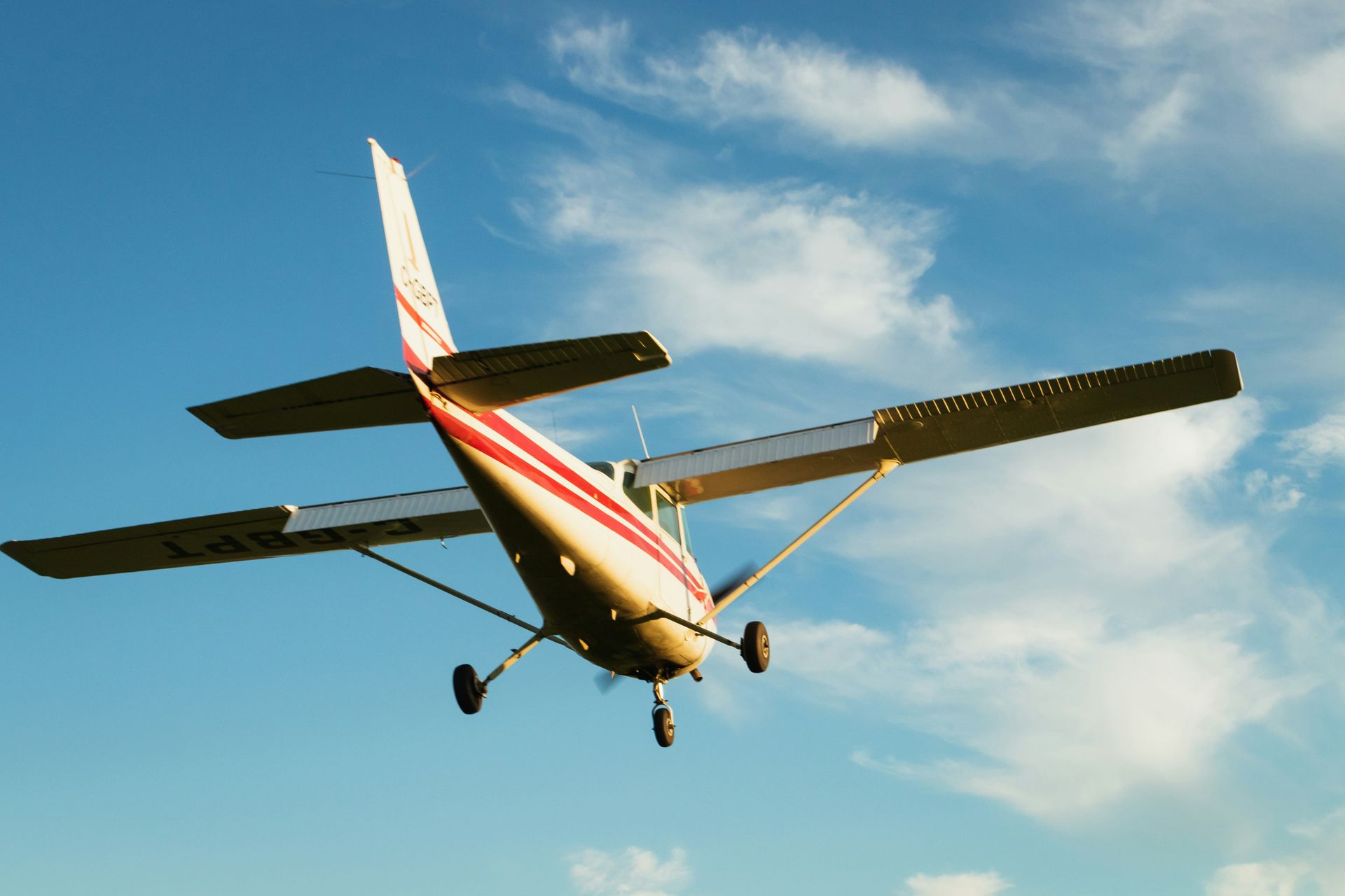 A small plane is flying through a cloudy blue sky