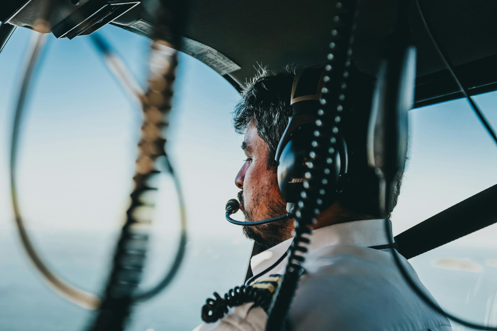 A man wearing headphones is sitting in the cockpit of a plane.