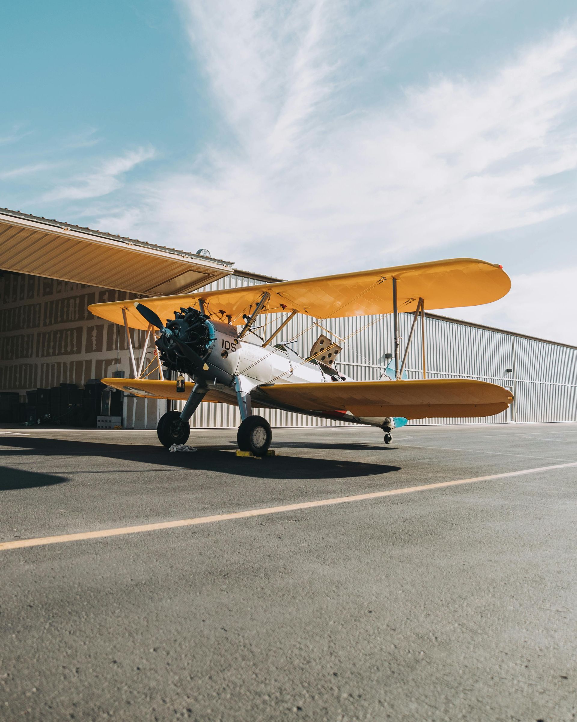 A yellow and white plane is parked in front of a building.