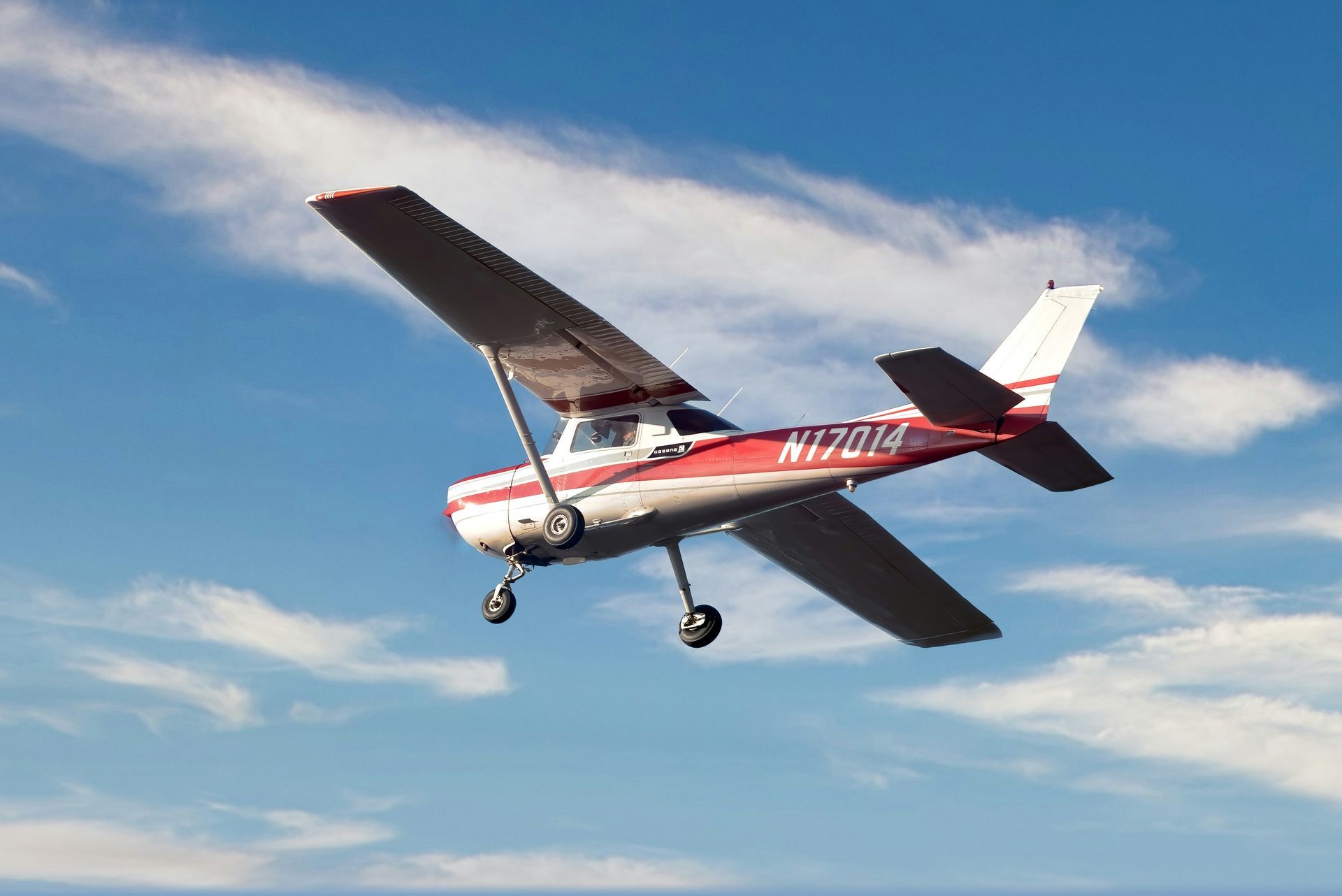 A small red and white airplane is flying in the sky.