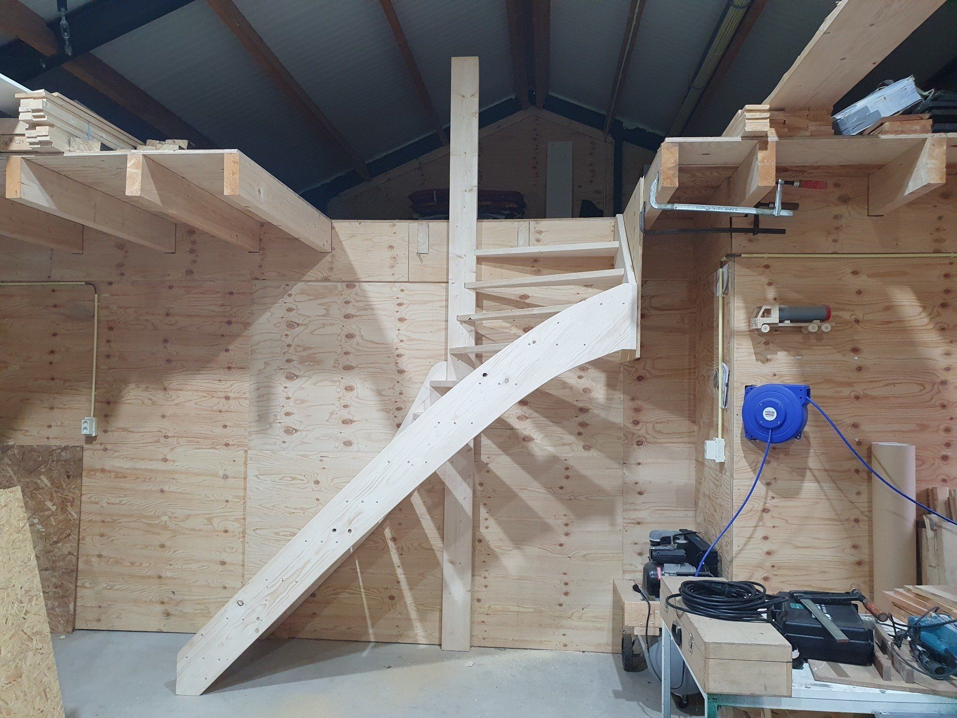 Houten interieur met een gebogen trap, in aanbouw in een werkplaats of hutframe.