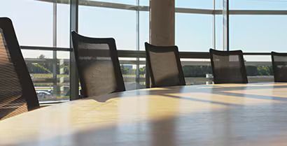 Empty conference room with black chairs around a sunlit table near large windows