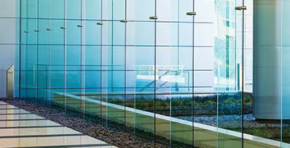 Modern glass office building with reflective blue windows and landscaped walkway