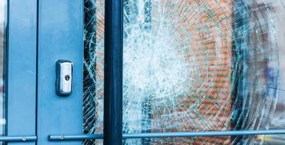 Blue door with a shattered glass pane and visible cracks in the window above the lock