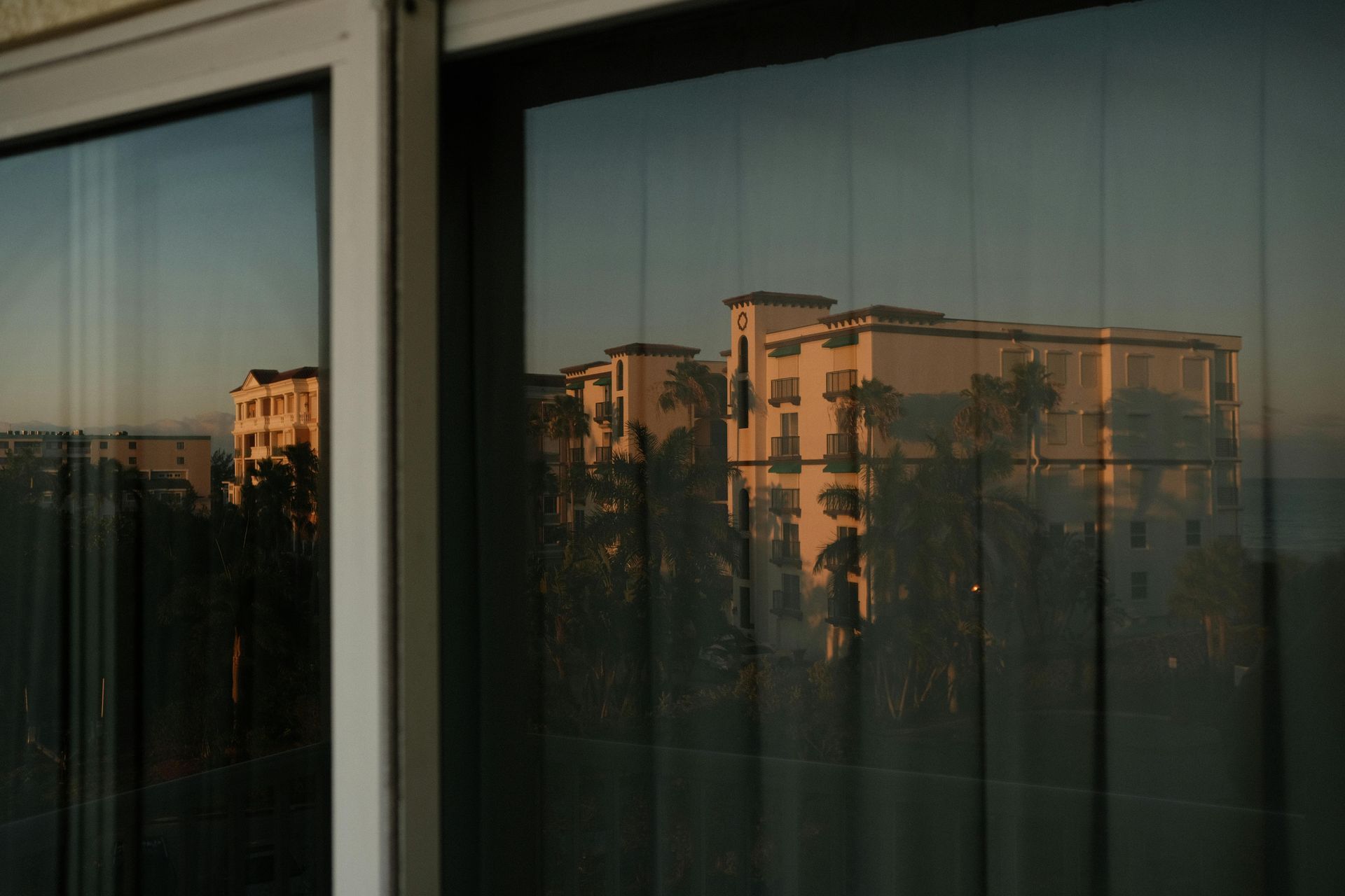 Apartment buildings reflected in a dark window at sunset