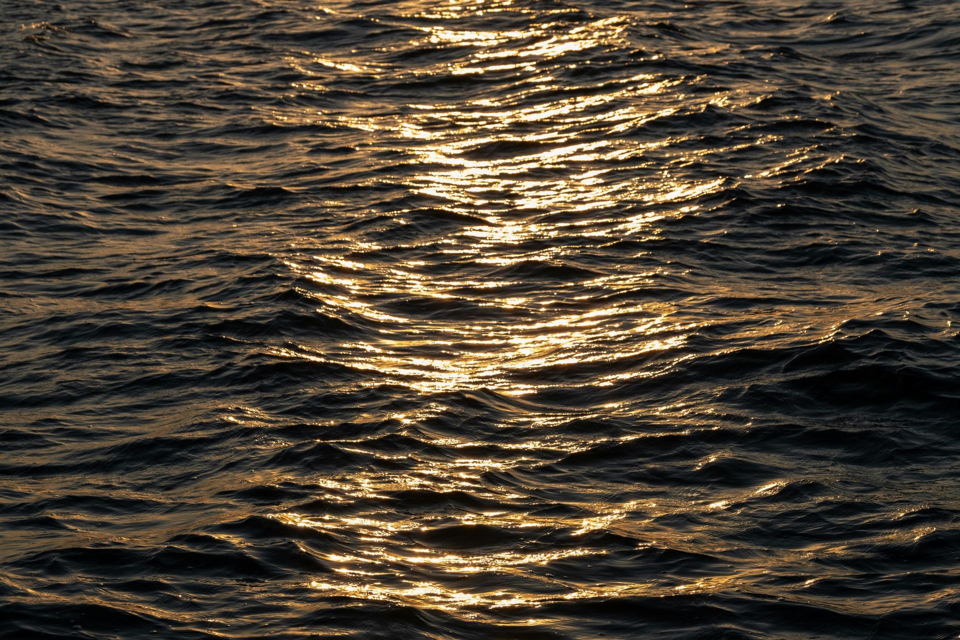 Sunlit ripples on dark ocean water at dusk