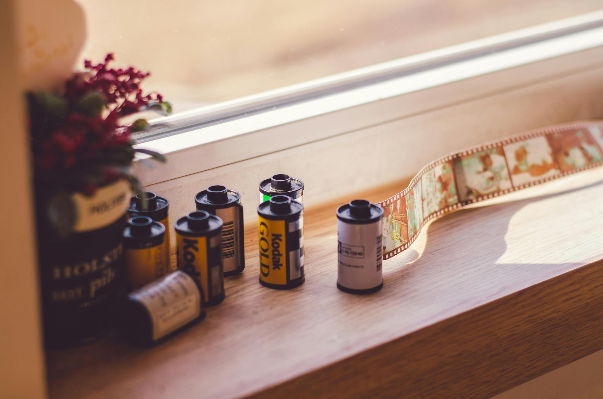 Small bottles and rolls of film on a wooden windowsill in warm sunlight
