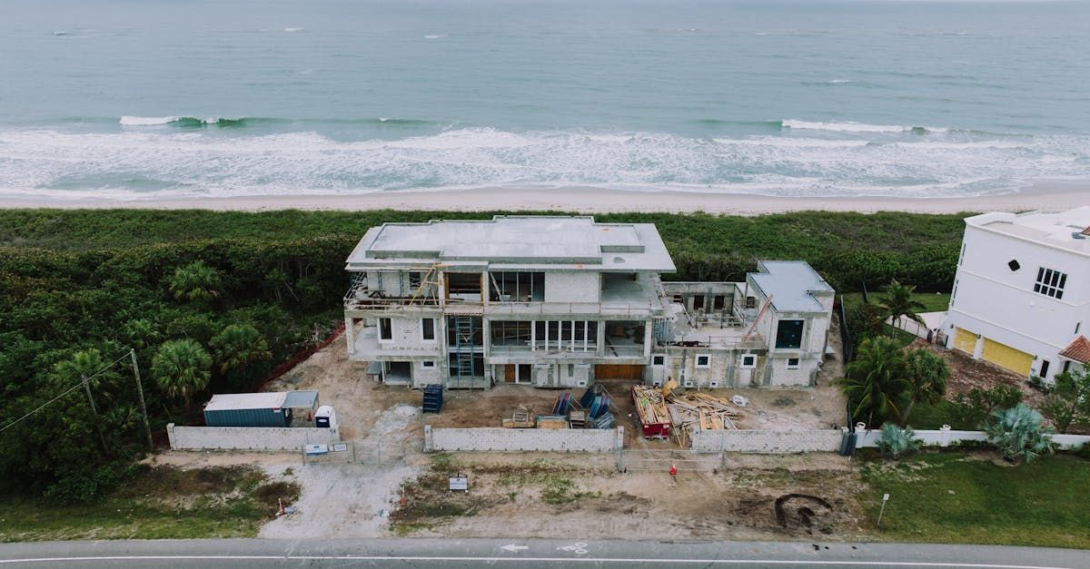 Aerial view of a beachfront house under construction beside the ocean and road.