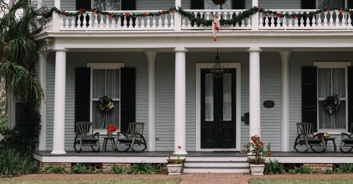 Front porch with white columns, black doors, and two bicycles on a gray house facade.