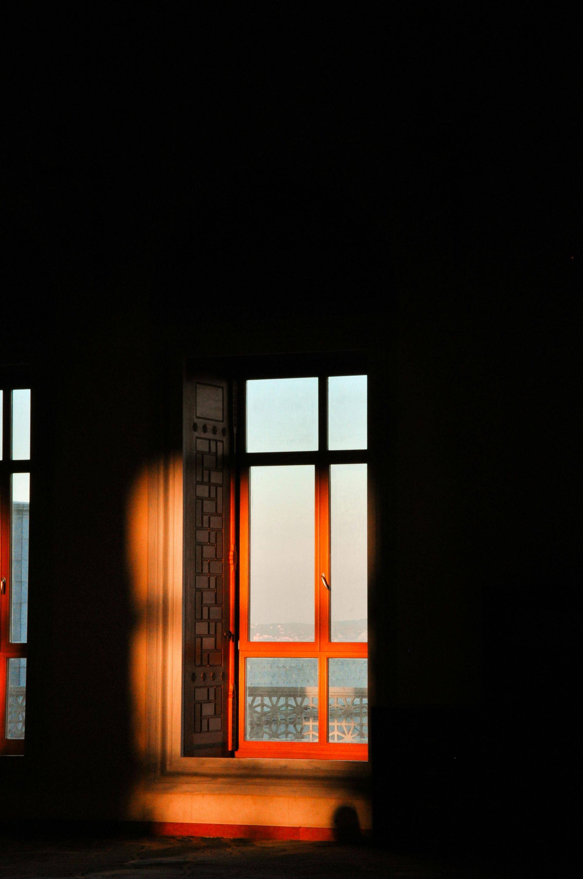 Sunlit window with orange glow in a dark room, casting light onto the floor