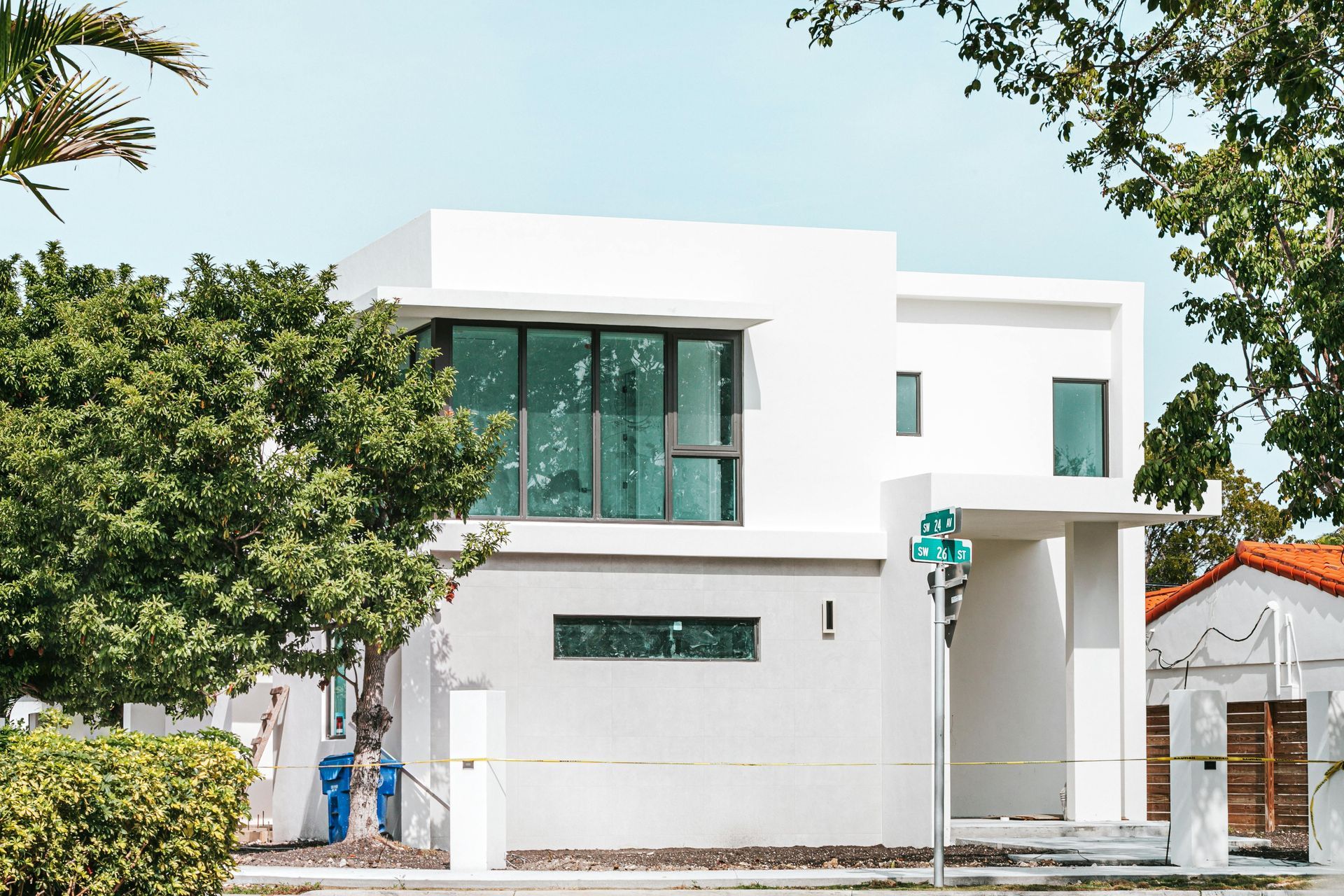 Modern white two-story house with large green-tinted windows and trees in front