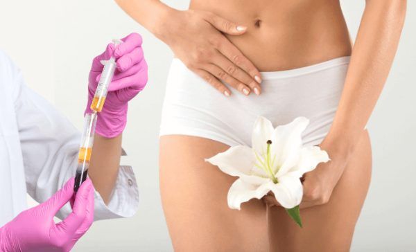 Woman in white underwear measuring her waist with a pink measuring tape against a gray background
