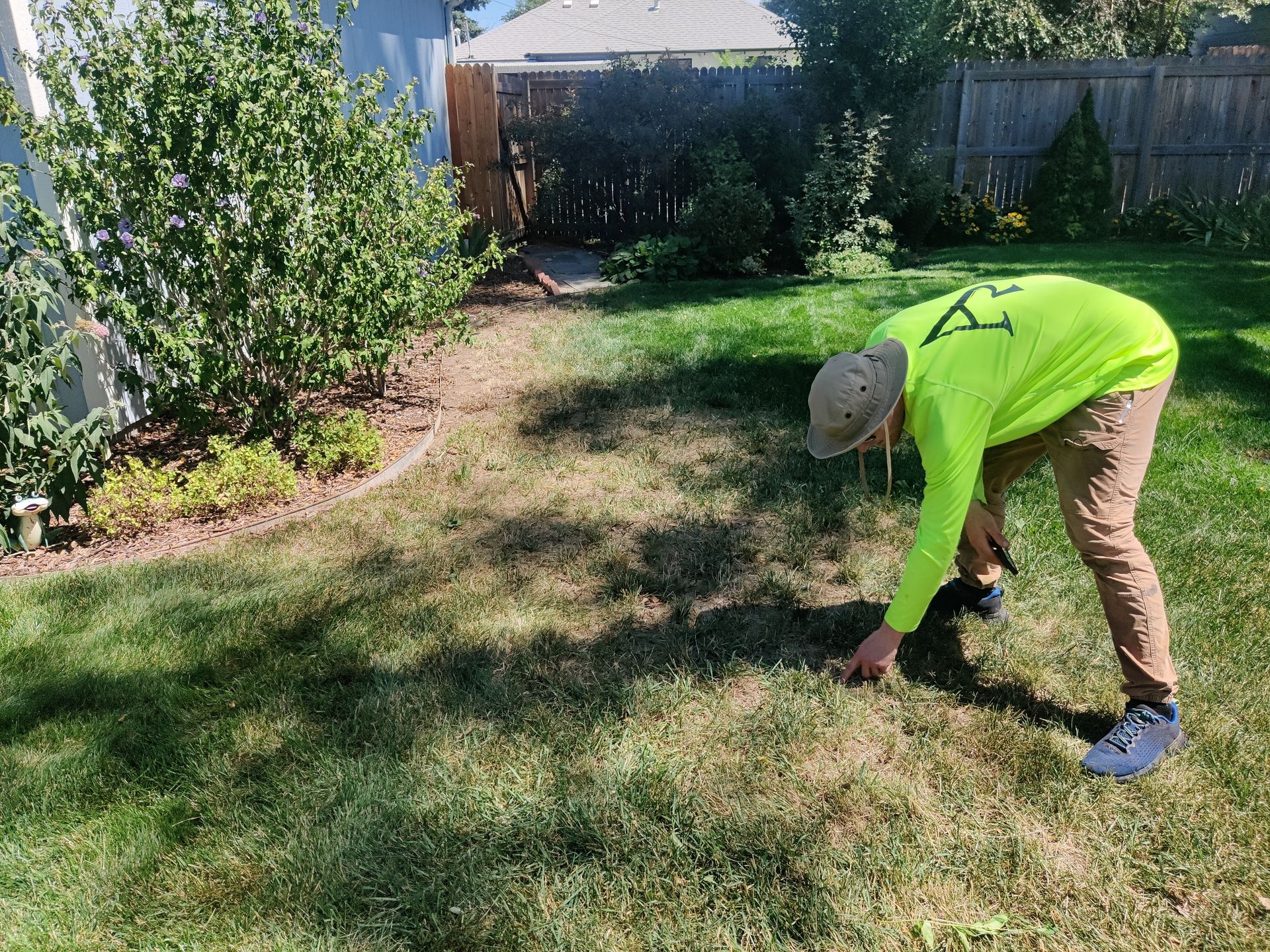 A man in a neon green shirt is bending over in the grass.