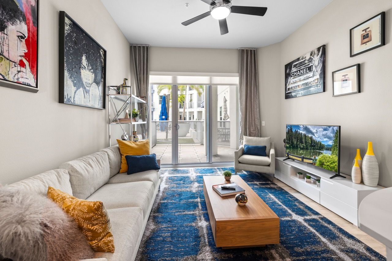 Modern living room in an apartment with a sofa, rug, coffee table, and balcony doors.