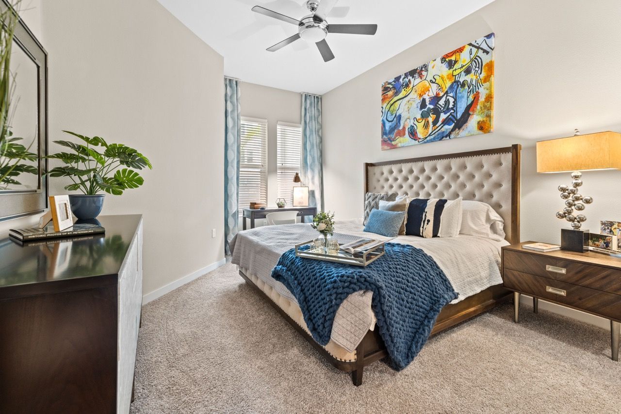 Bedroom in a modern apartment with a tufted headboard, nightstands, and a blue knit throw at 930 Central Flats, offering apartments in St. Petersburg.