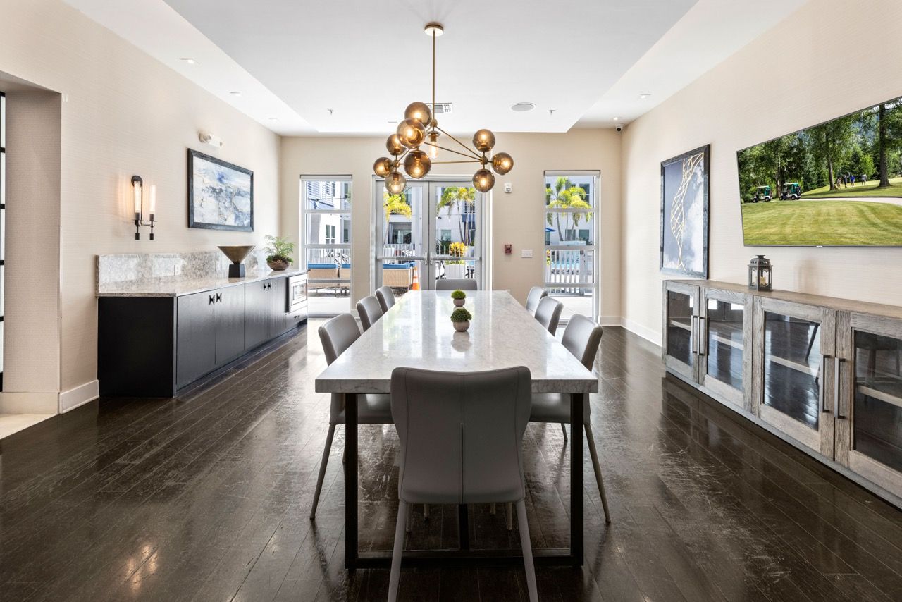 Bright community room with a long marble dining table, chairs, and built-in cabinets at 930 Central Flats, offering apartments for rent in St. Petersburg.